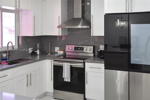 kitchen featuring wall chimney range hood, sink, appliances with stainless steel finishes, tasteful backsplash, and white cabinetry