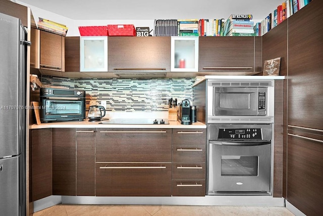 kitchen featuring dark brown cabinets, light tile patterned floors, and stainless steel appliances