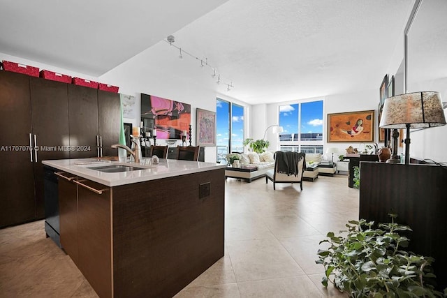 kitchen with a center island with sink, dark brown cabinets, floor to ceiling windows, and dishwasher