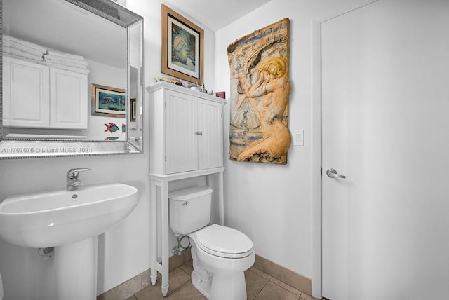 bathroom with toilet, tile patterned floors, and sink