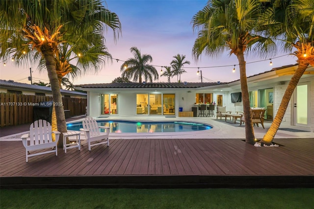 pool at dusk featuring a deck