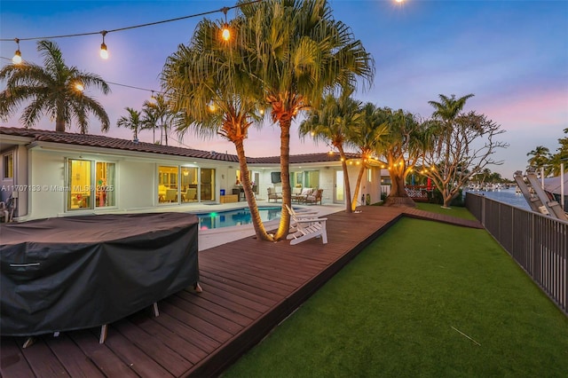 deck at dusk with a fenced in pool, a grill, and a yard