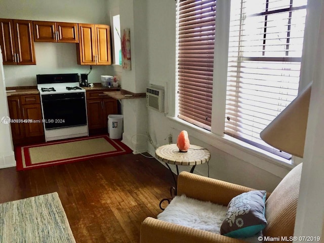 kitchen featuring dark hardwood / wood-style flooring, white range oven, and a wall unit AC