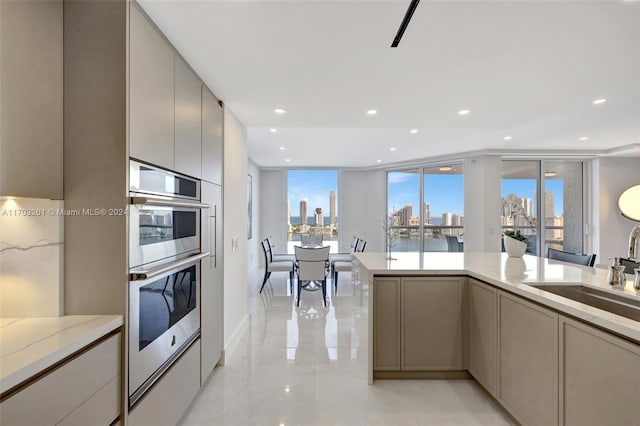 kitchen featuring gray cabinetry, light stone counters, sink, and stainless steel double oven