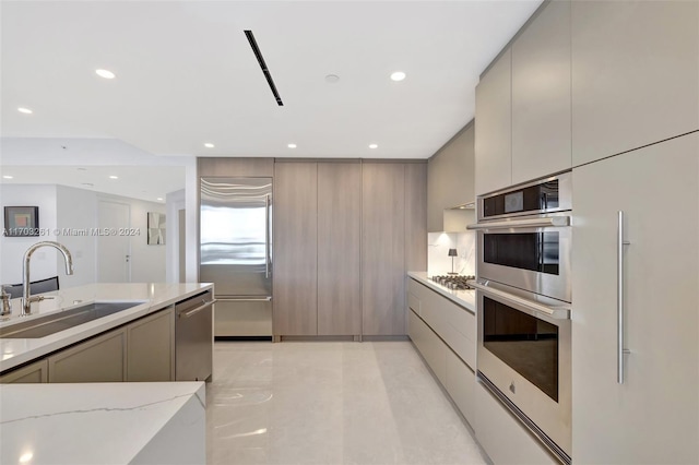 kitchen featuring light stone counters, gray cabinets, sink, and stainless steel appliances