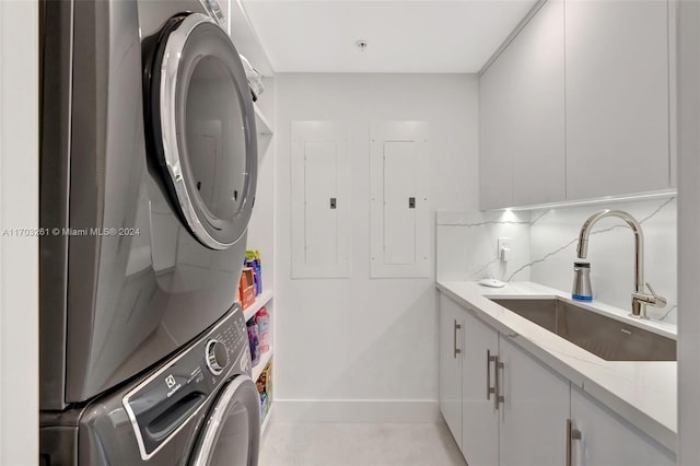 laundry room featuring cabinets, stacked washing maching and dryer, sink, and electric panel