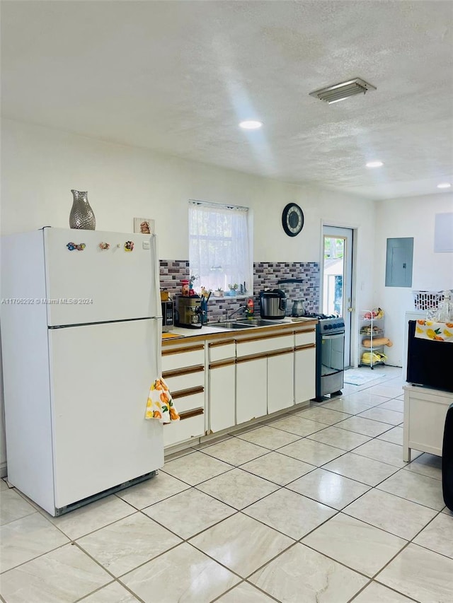 kitchen with stainless steel gas stove, white fridge, a wealth of natural light, and electric panel