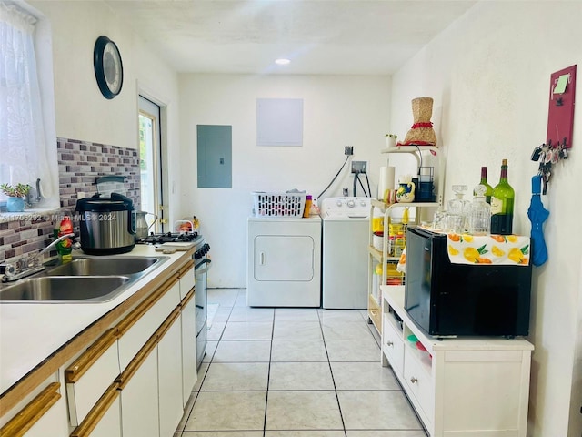 kitchen featuring washing machine and dryer, electric panel, white cabinetry, and sink