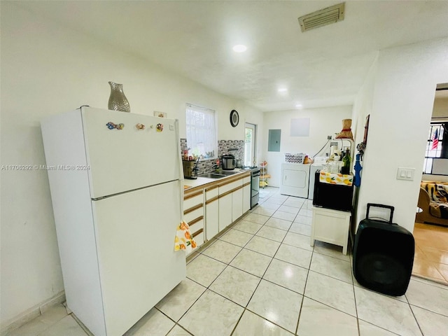 kitchen with white cabinetry, white refrigerator, electric panel, washer / clothes dryer, and light tile patterned flooring