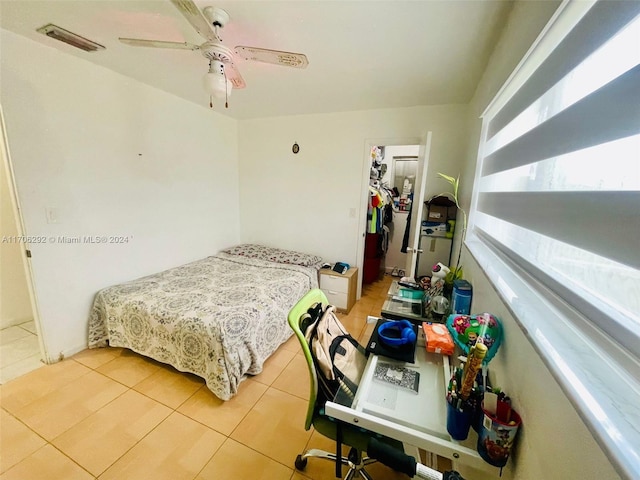 bedroom with a walk in closet, ceiling fan, a closet, and light tile patterned floors