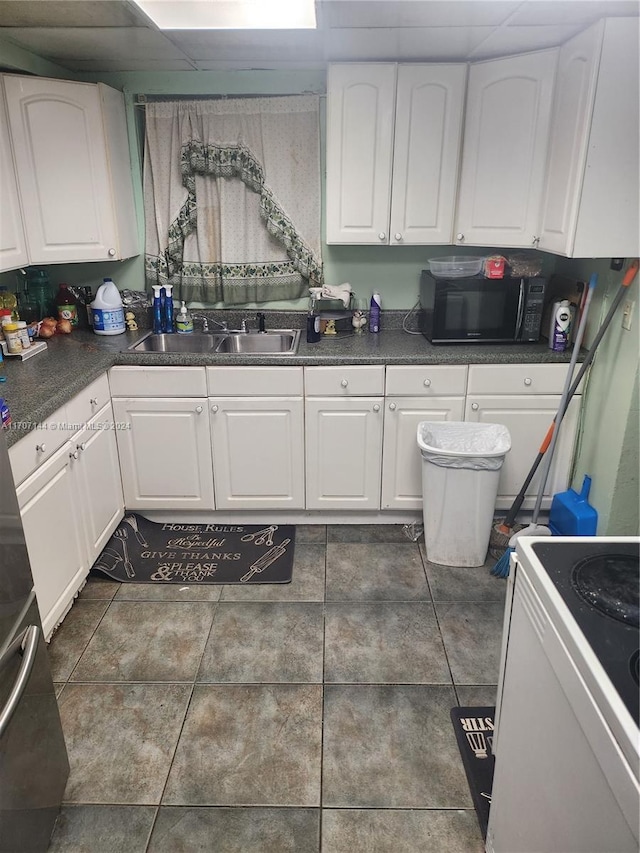 kitchen featuring white cabinets, dark tile patterned floors, sink, and white stove