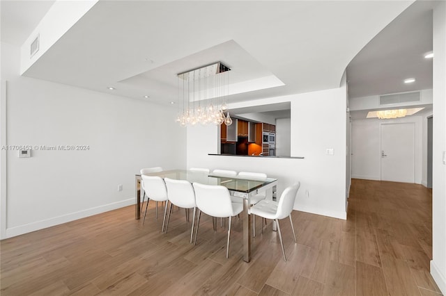 dining area featuring a raised ceiling and hardwood / wood-style floors