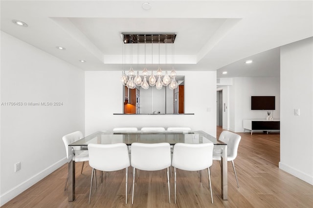 dining area with a raised ceiling and light wood-type flooring