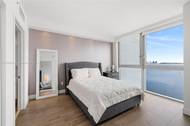 bedroom with a water view and light wood-type flooring