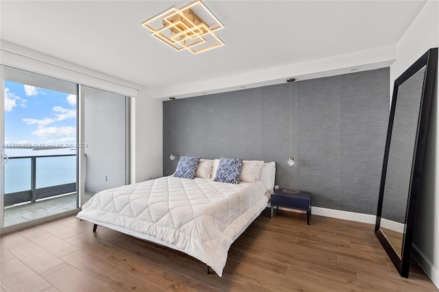 bedroom featuring access to exterior, a water view, and wood-type flooring