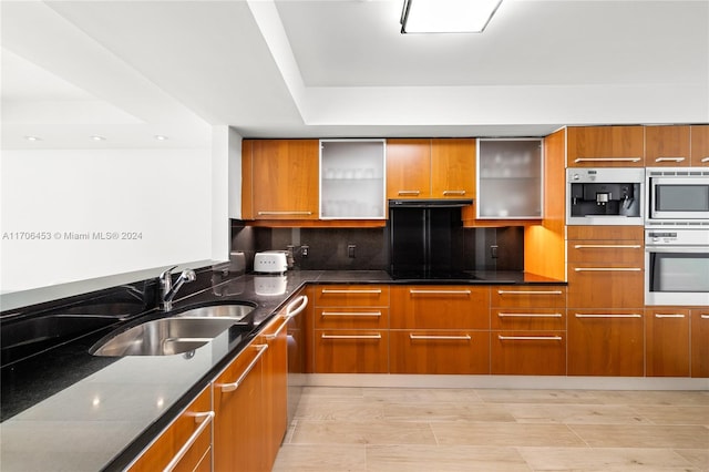 kitchen featuring dark stone countertops, sink, light wood-type flooring, and appliances with stainless steel finishes