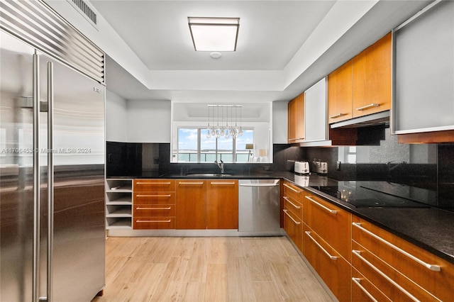 kitchen featuring light hardwood / wood-style floors, sink, appliances with stainless steel finishes, and a tray ceiling