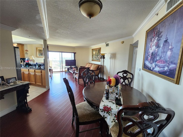 dining area featuring light hardwood / wood-style floors, ornamental molding, and a textured ceiling