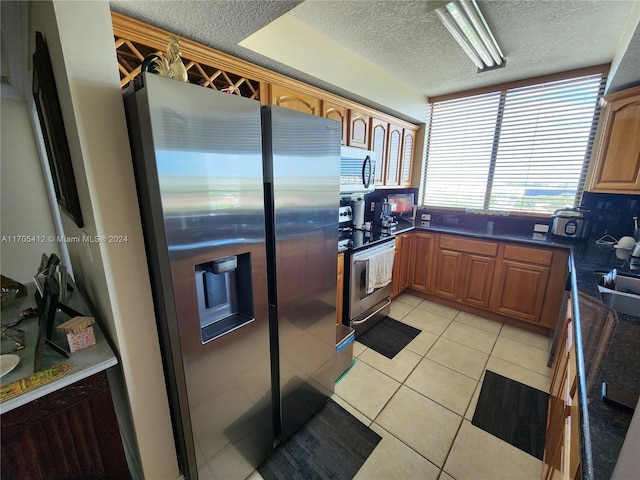 kitchen with light tile patterned floors, stainless steel appliances, and a textured ceiling