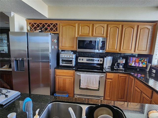 kitchen with backsplash, dark stone countertops, and stainless steel appliances