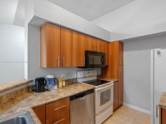 kitchen featuring appliances with stainless steel finishes, a textured ceiling, light tile patterned floors, and lofted ceiling