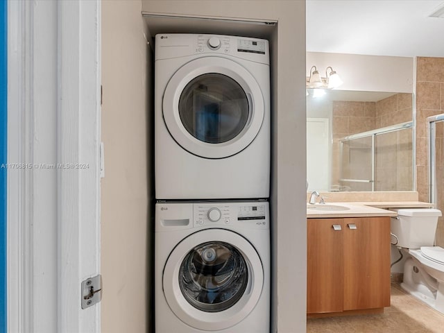 washroom with light tile patterned flooring, sink, and stacked washer and clothes dryer