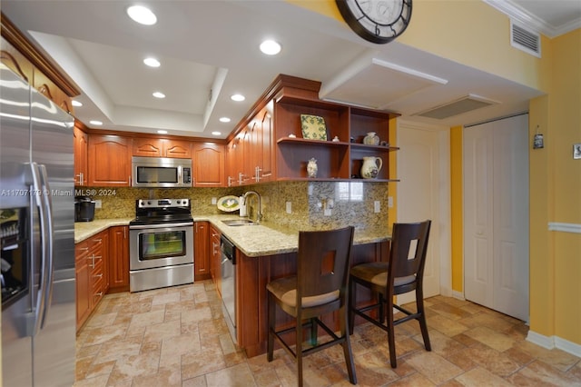 kitchen with light stone countertops, sink, stainless steel appliances, tasteful backsplash, and a breakfast bar area