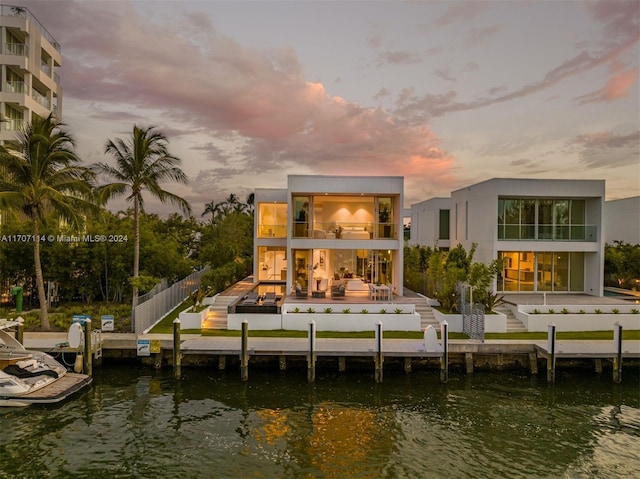 back house at dusk featuring a water view and a balcony