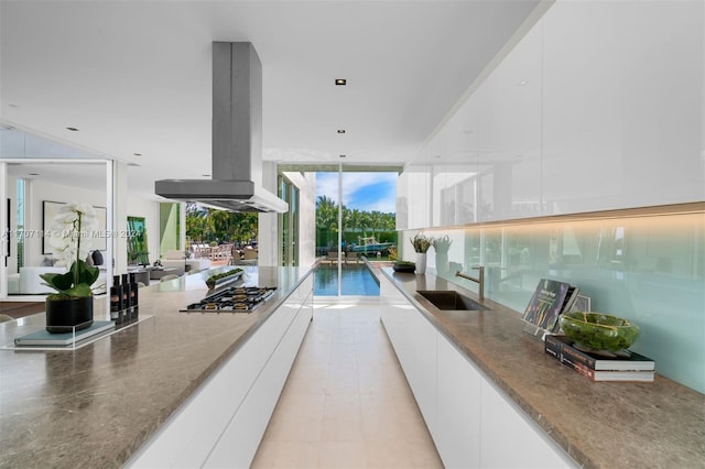 interior space featuring island exhaust hood, white cabinetry, sink, and floor to ceiling windows