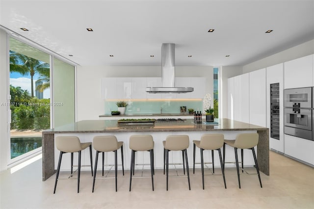 kitchen with white cabinets, wall chimney exhaust hood, and plenty of natural light