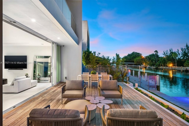 balcony at dusk featuring a water view