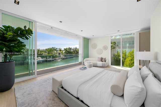 bedroom with access to exterior, floor to ceiling windows, a water view, and light hardwood / wood-style flooring