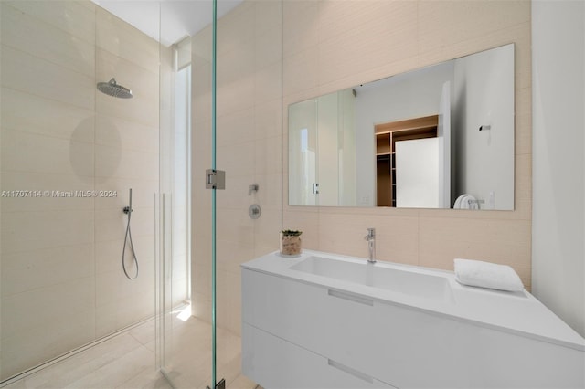 bathroom featuring vanity, a shower with door, and tile walls