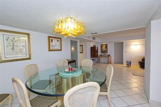 dining area with a chandelier, light tile patterned floors, and a textured ceiling