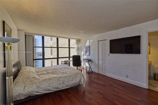 bedroom with floor to ceiling windows, a textured ceiling, ensuite bathroom, and dark hardwood / wood-style floors