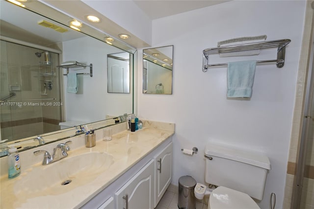 bathroom with tile patterned floors, vanity, toilet, and a shower with shower door