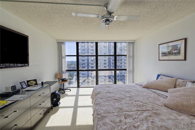 carpeted bedroom featuring floor to ceiling windows, ceiling fan, and a textured ceiling