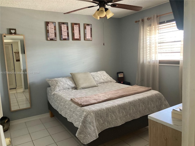 bedroom with ceiling fan, light tile patterned floors, and a textured ceiling