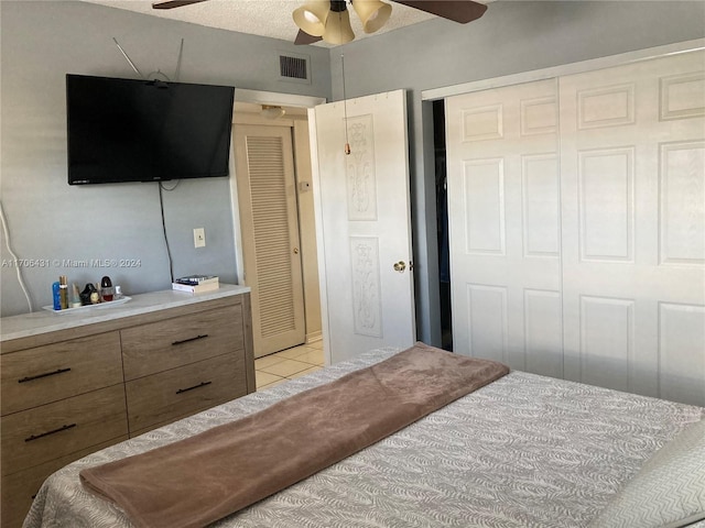 bedroom featuring ceiling fan, light tile patterned floors, a textured ceiling, and a closet