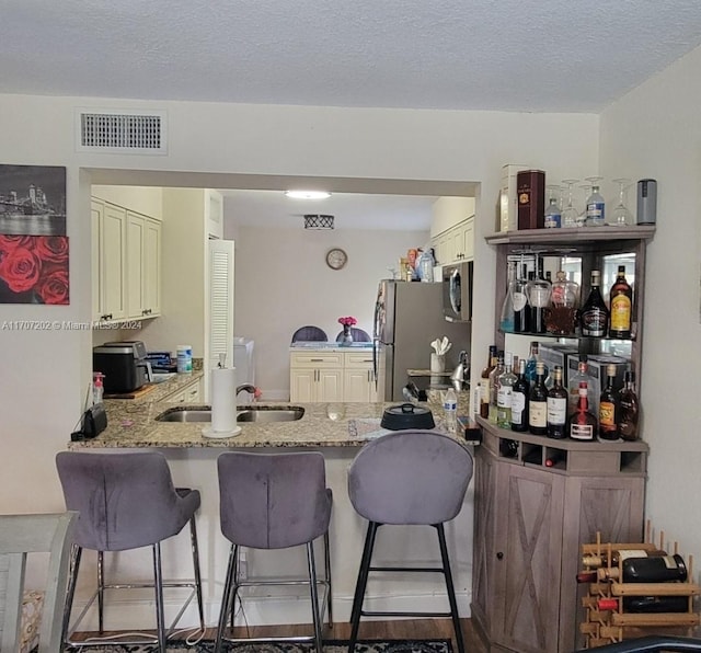 kitchen featuring sink, stainless steel appliances, a kitchen breakfast bar, light stone counters, and kitchen peninsula