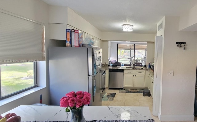 kitchen with stone counters, white cabinetry, sink, light tile patterned floors, and appliances with stainless steel finishes