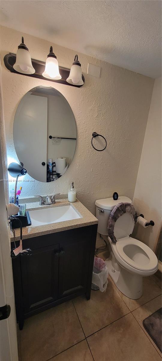 bathroom with tile patterned flooring, vanity, a textured ceiling, and toilet