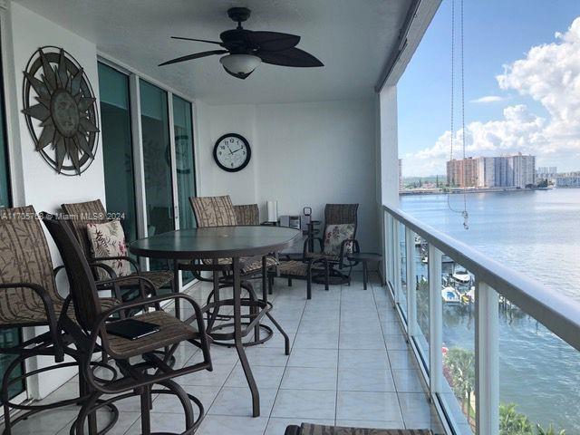 balcony with ceiling fan and a water view