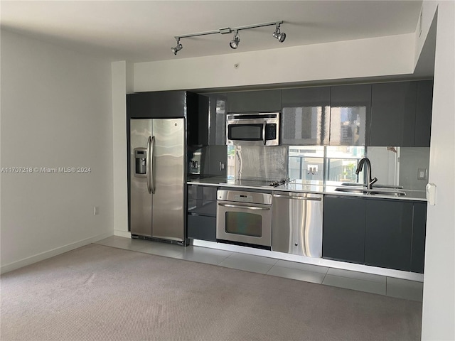 kitchen with light carpet, rail lighting, sink, appliances with stainless steel finishes, and stainless steel counters