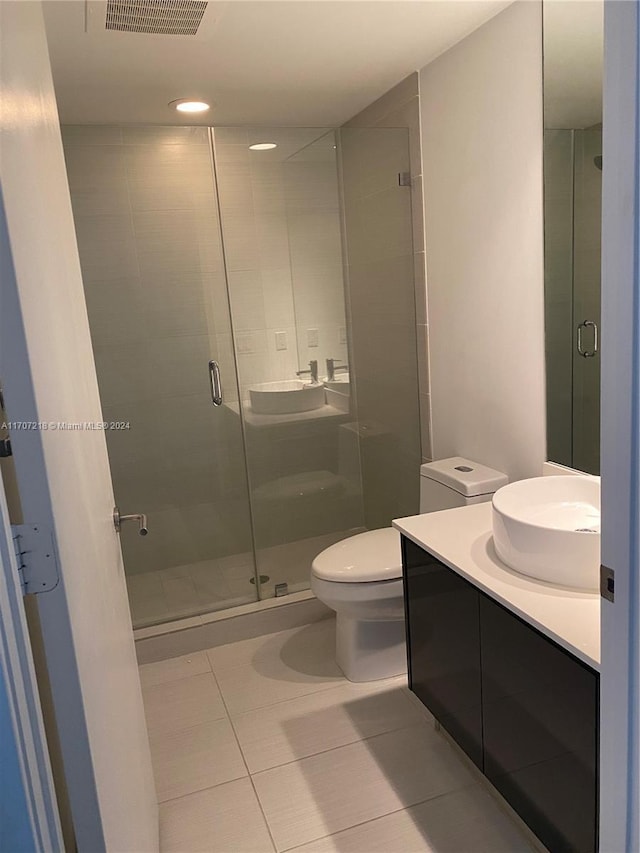 bathroom with tile patterned flooring, vanity, toilet, and a shower with door