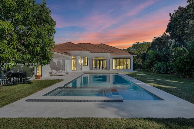 pool at dusk featuring an outbuilding, a patio, and a yard