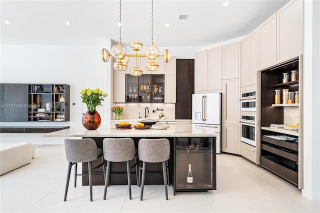 kitchen with light tile patterned flooring, a breakfast bar area, tasteful backsplash, decorative light fixtures, and white appliances