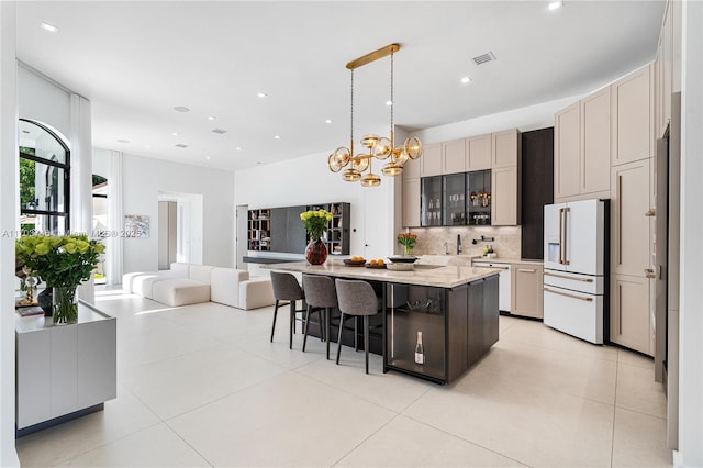 kitchen featuring high end white refrigerator, a center island, a kitchen breakfast bar, pendant lighting, and decorative backsplash