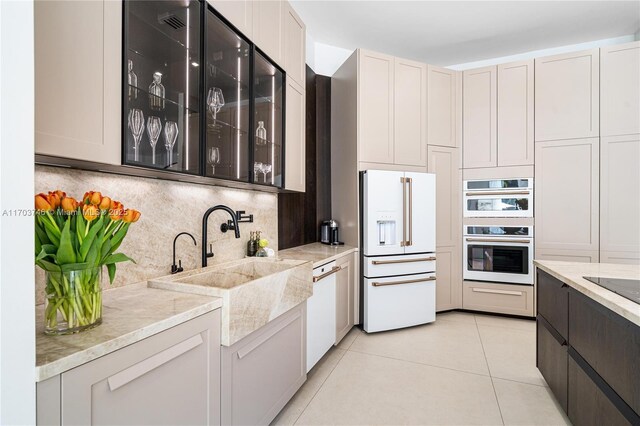 kitchen featuring white cabinetry, light tile patterned floors, light stone counters, and white appliances