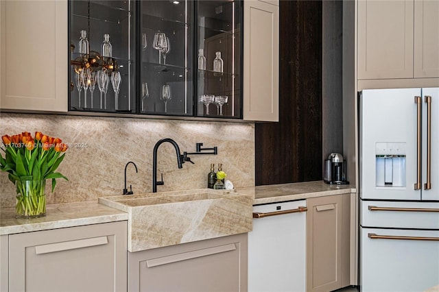 bar with high end white refrigerator, gray cabinetry, backsplash, and sink